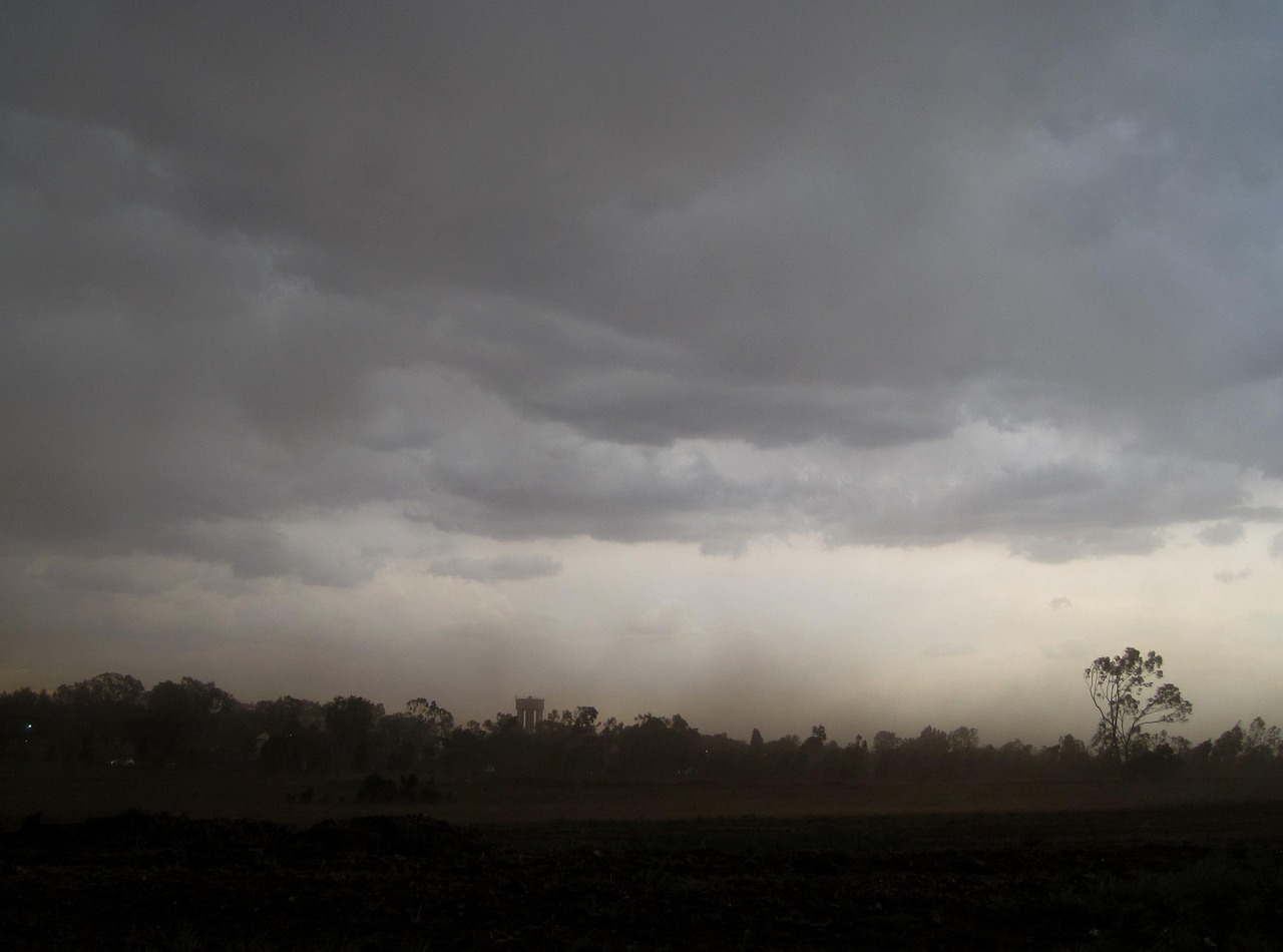 Nuvens escuras de tempestade sobre paisagem rural com chuva ao fundo; ciclone traz temporais e granizo ao Sul